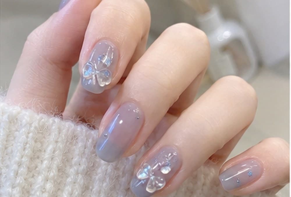 Almond nails in a soft lavender finish with small pearl and floral accents